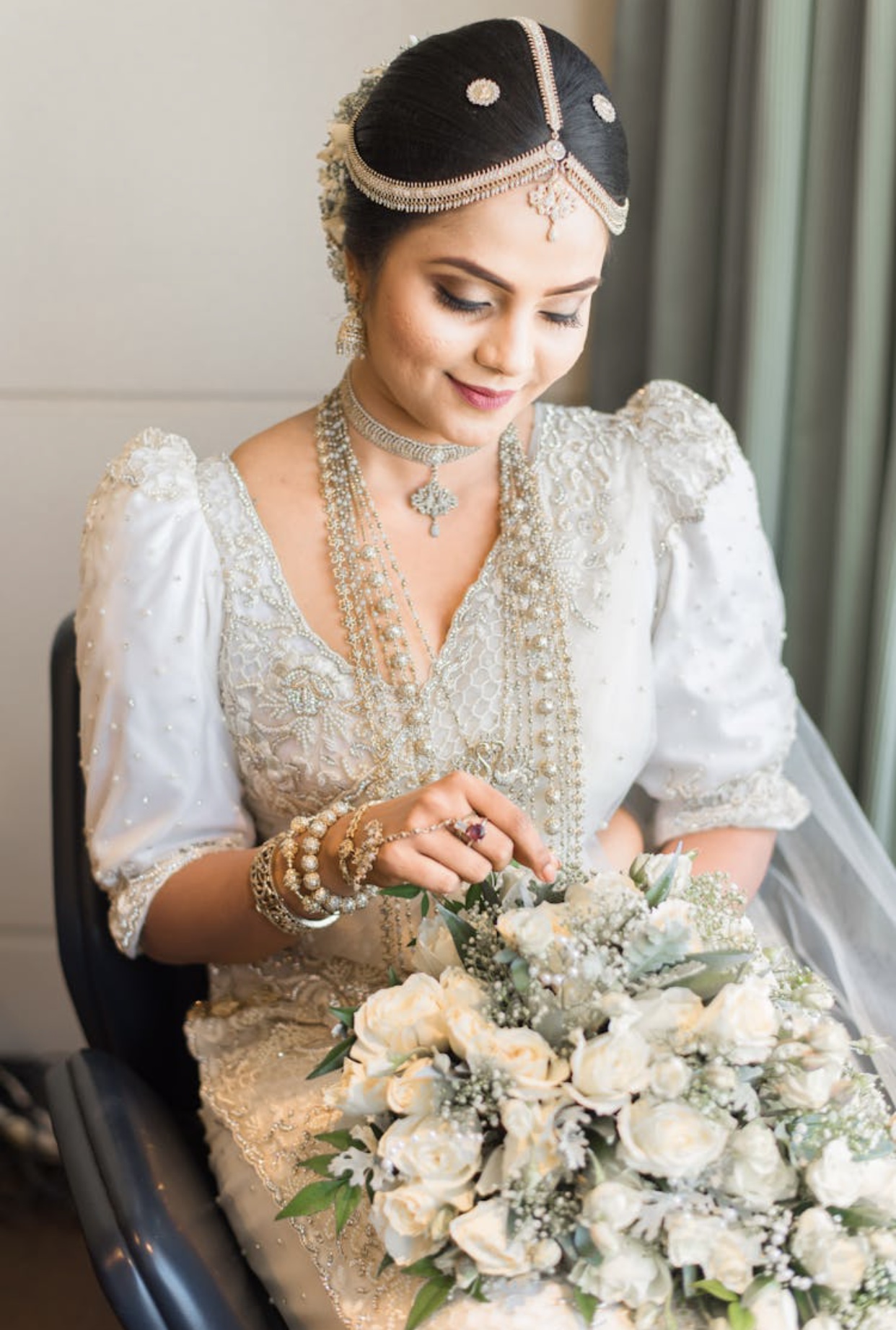 Hindu bride in a white wedding dress with puffed 3/4 length sleeves and intricate beadwork.