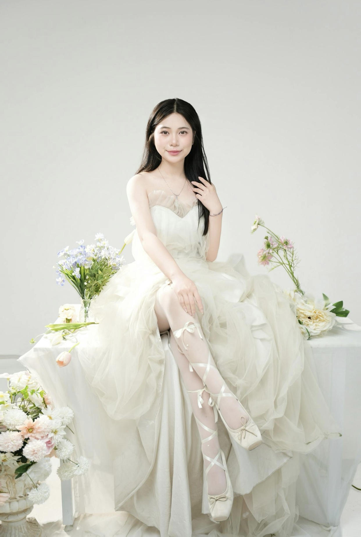 Asian bride in a white strapless wedding dress with a ruffled sweetheart bodice and flowing ruffled skirt paired with laved up ballet slippers. 