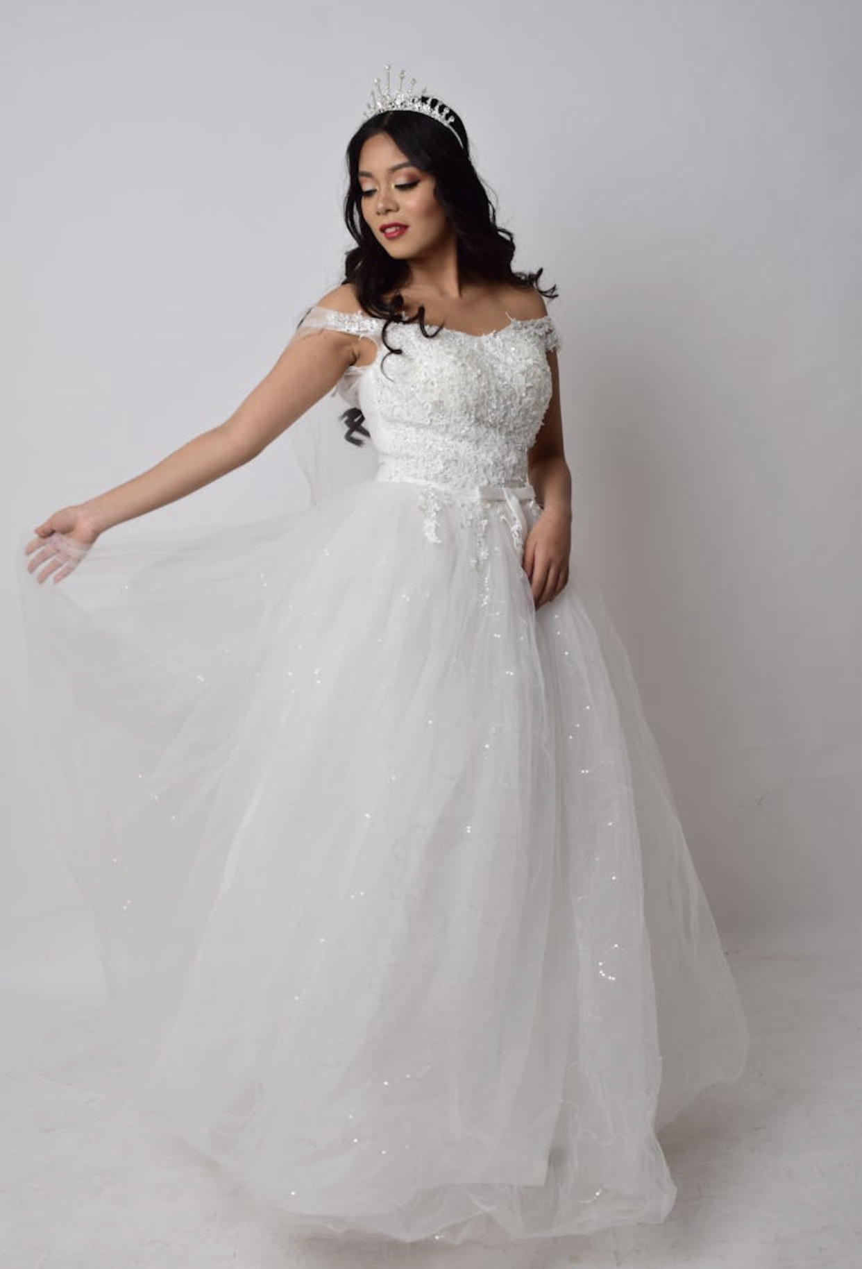 Hispanic bride in an off the shoulder white tulle wedding gown with a lace bodice and silver crown.