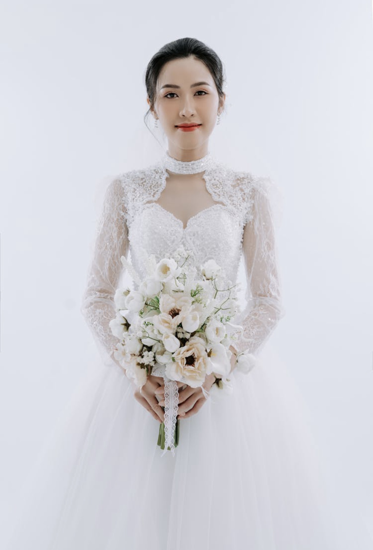 Asian bride in a pure white wedding gown with a lace bodice, full tulle skirt and lace bolero jacket.