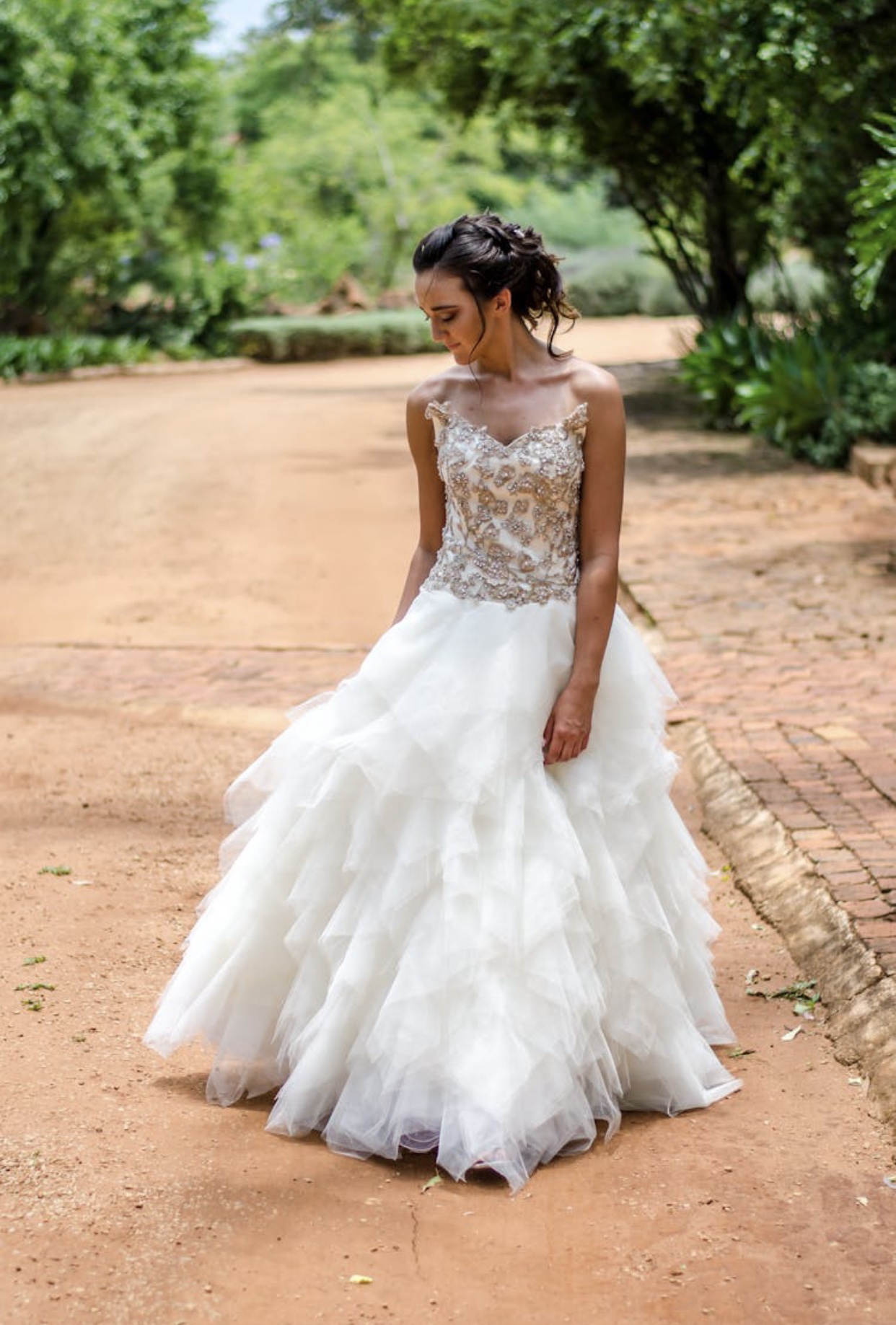 Brunette bride in a heavily beaded ivory bodice with sweetheart neckline and a pure white heavily ruffled organza full skirt.