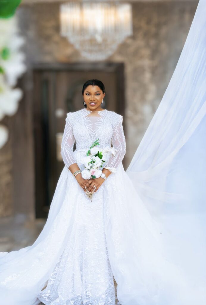 African American bride in a sheer long sleeve organza wedding gown with a beaded bodice and high neckline