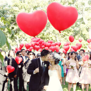 Bride and groom with red heart balloon send off