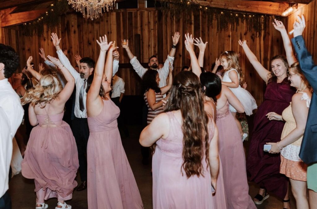 Bridesmaids dressed in blush dancing at a summer wedding at Steel Magnolia Barn