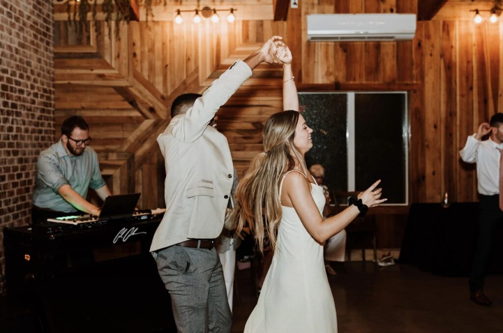 Guests dancing and twirling on the dance floor at a summer wedding at Steel Magnolia Barn