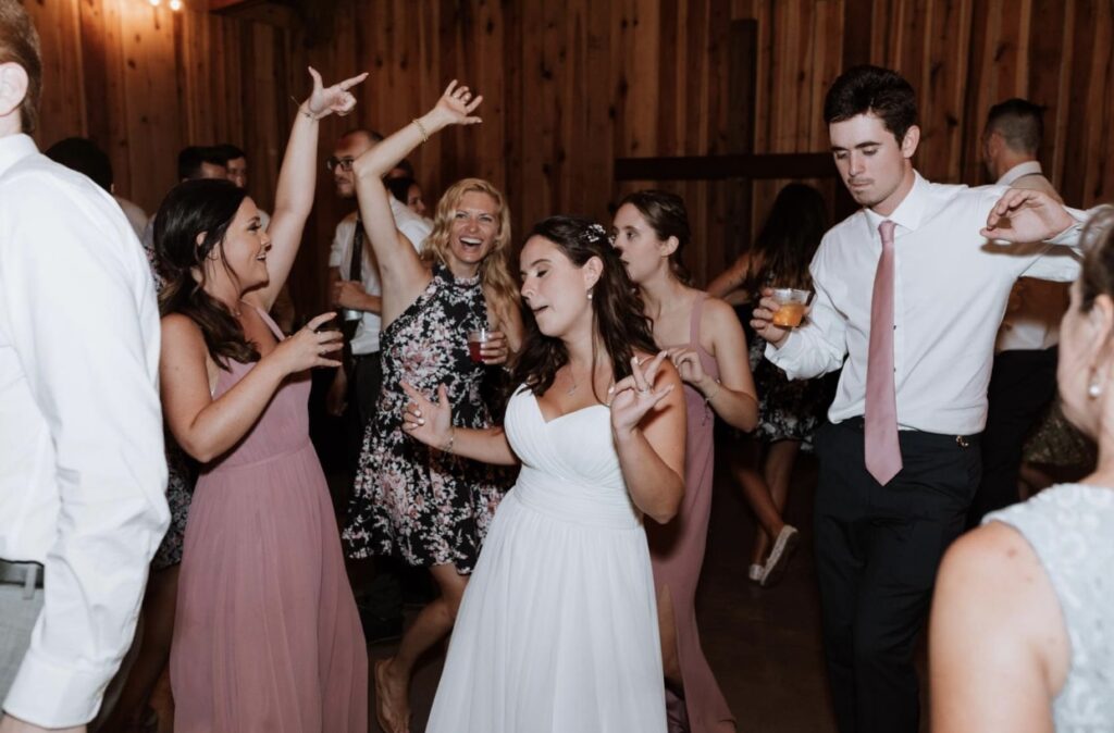 The bride dances with her bridesmaids at her summer wedding at Steel Magnolia Barn