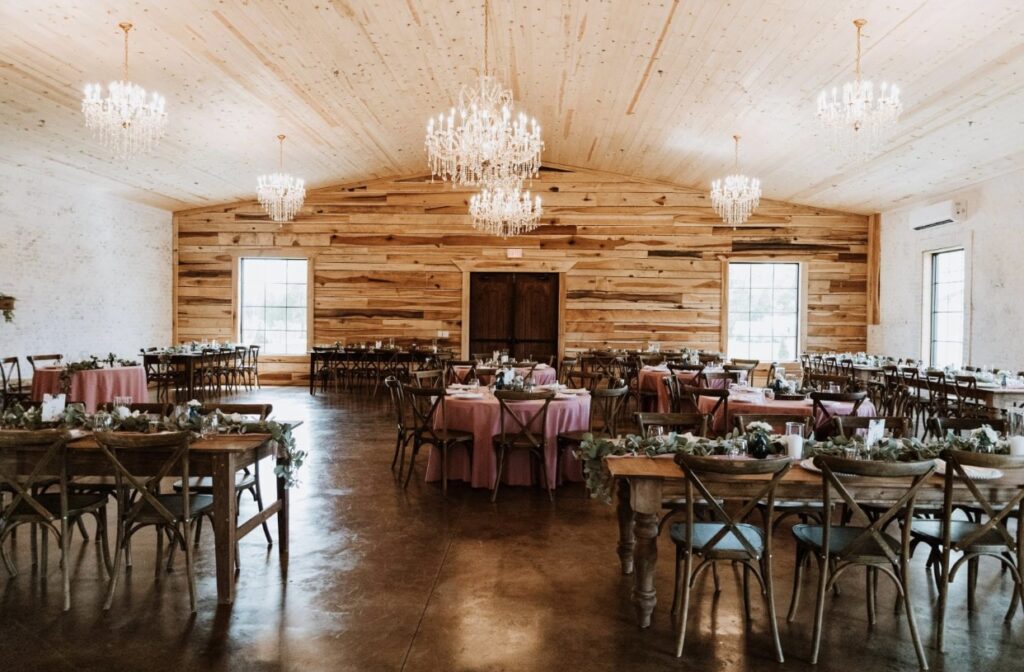 Steel Magnolia Barn is elegantly decorated for a summer wedding. The crystal chandeliers and cedar wood walls are set off by rose colored table cloths. 